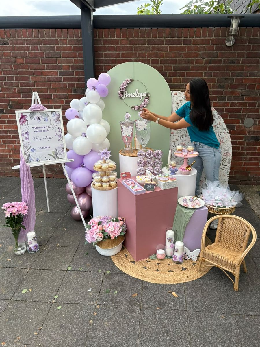 Eleni beim Aufbau einer Taufdeko in Flieder und Salbeigrün – sie richtet die Gläser auf dem Sweet Table